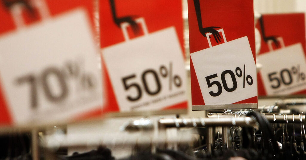 Sale signs on a red background showing 50% off discount and 70% off discount, in a clothing store. 